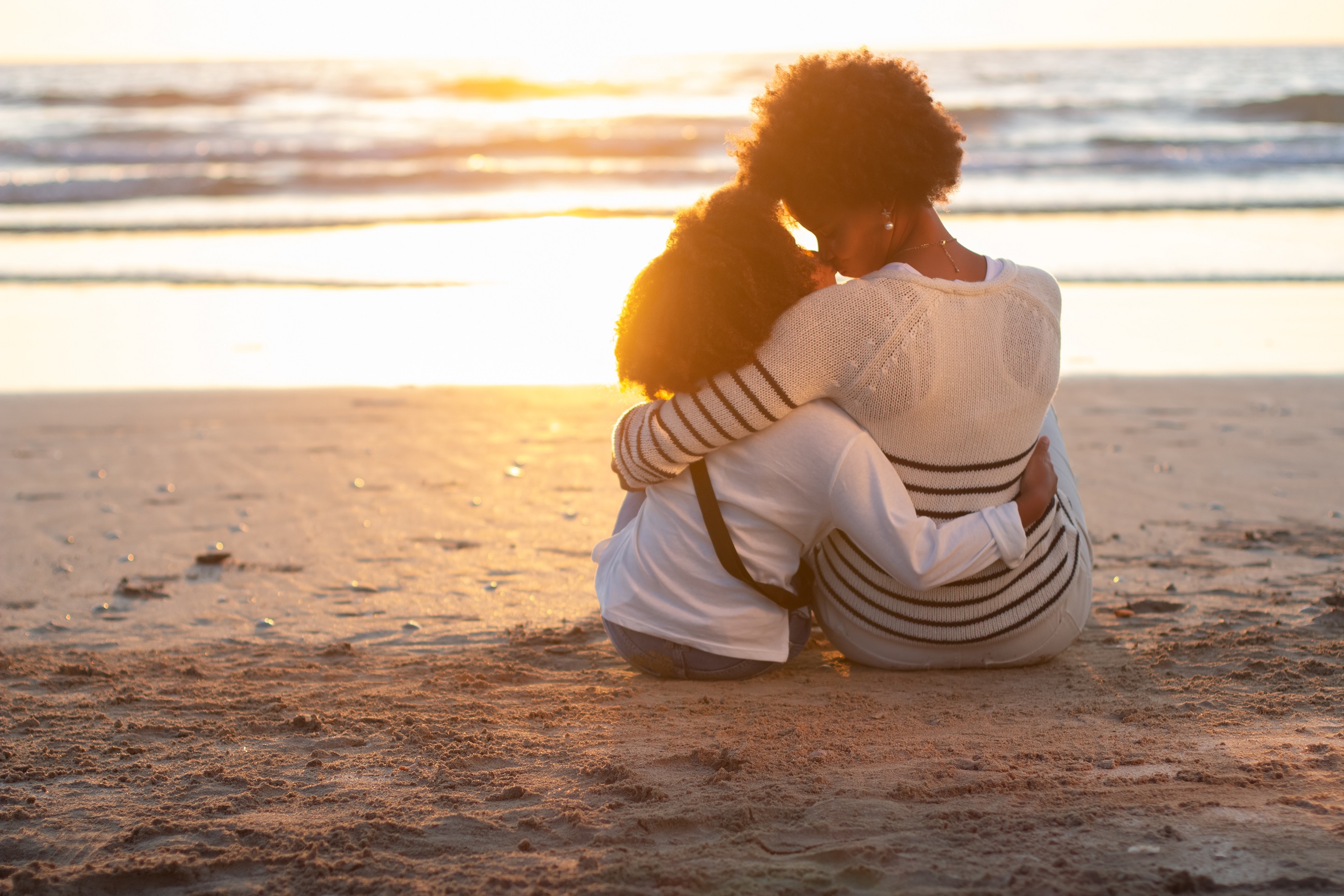Back view of loving mother and daughter looking at sunset
